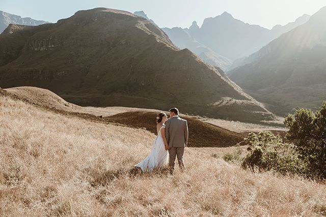 Bride and groom standing on a hill overlooking the Drakensberg foothills